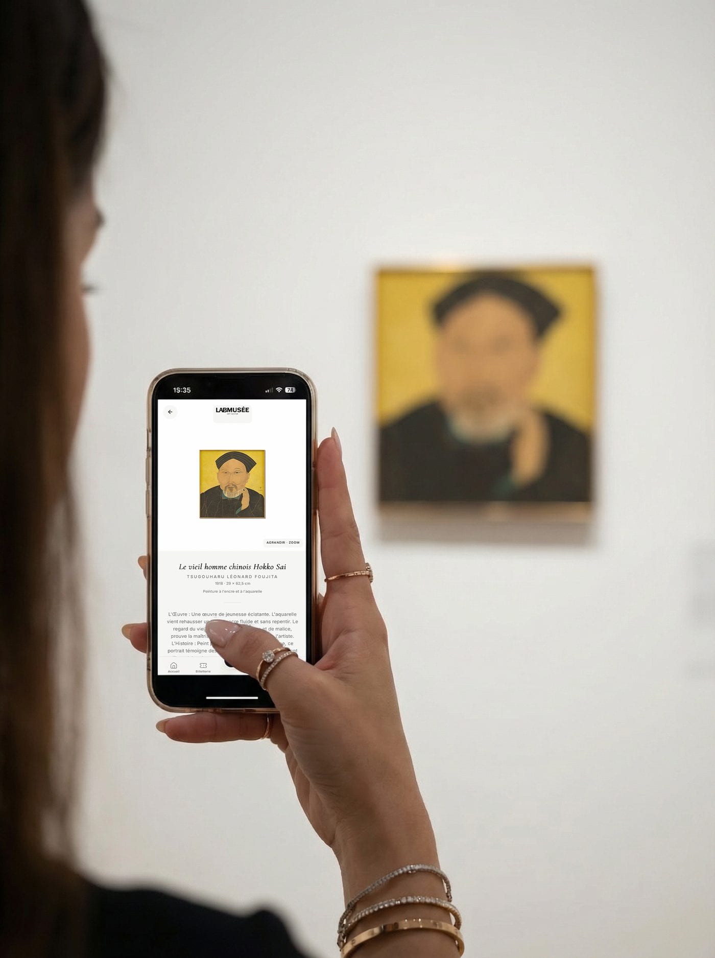 Une visiteuse lit sur l'application la notice du Vieil homme chinois Hokko Sai de Foujita, debout devant le tableau