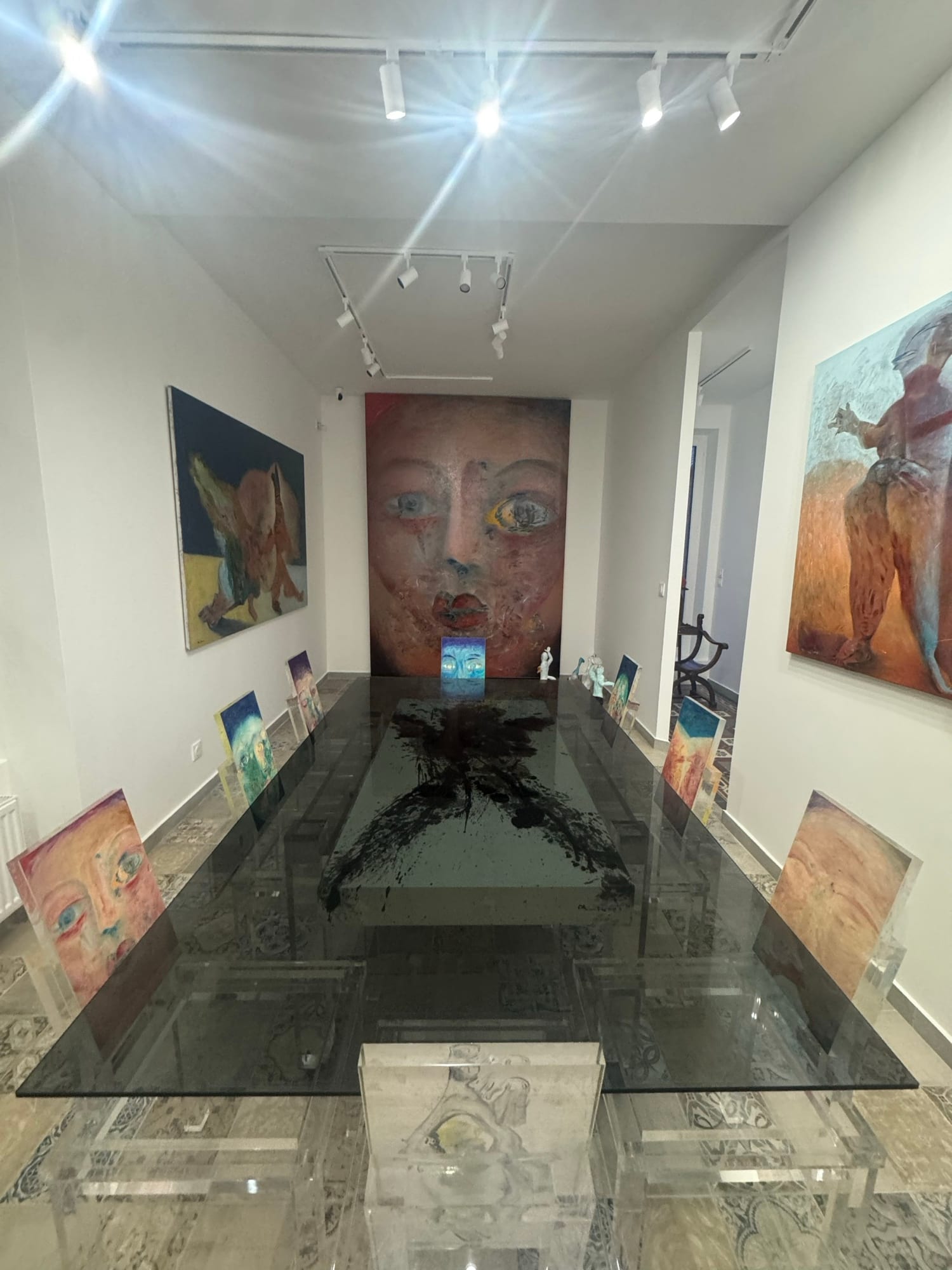 The glass table of “A Table Face”, surrounded by Alixe Fu's canvases