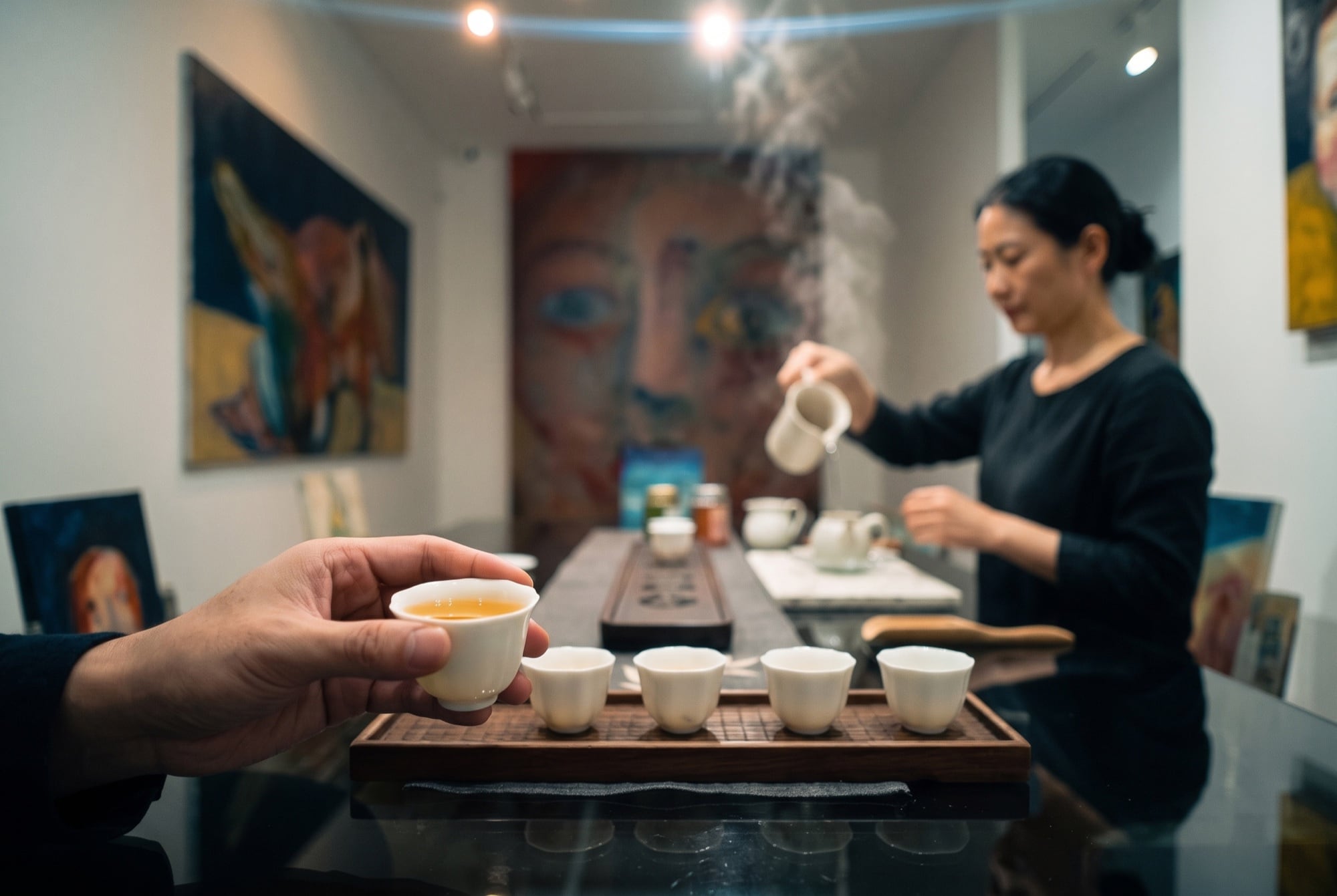 Mood image: a hand lifts a cup of tea while the host pours in the background