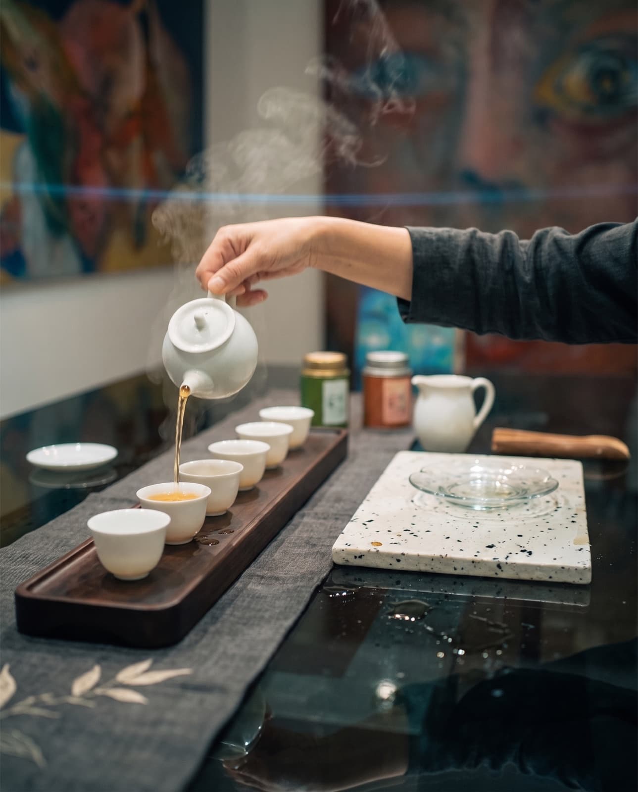 Mood image: tea poured in a thin stream into a row of porcelain cups